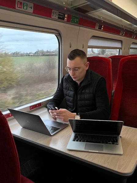 Brad Matthews working across two laptops on a train